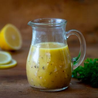 Bottle of Homemade Greek Vinaigrette on a wooden table.