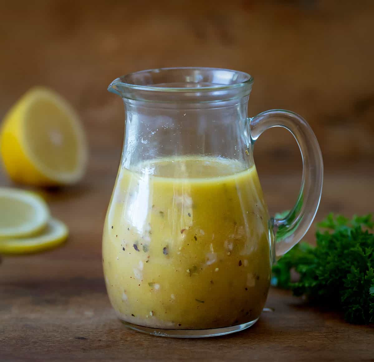 Bottle of Homemade Greek Vinaigrette on a wooden table. 