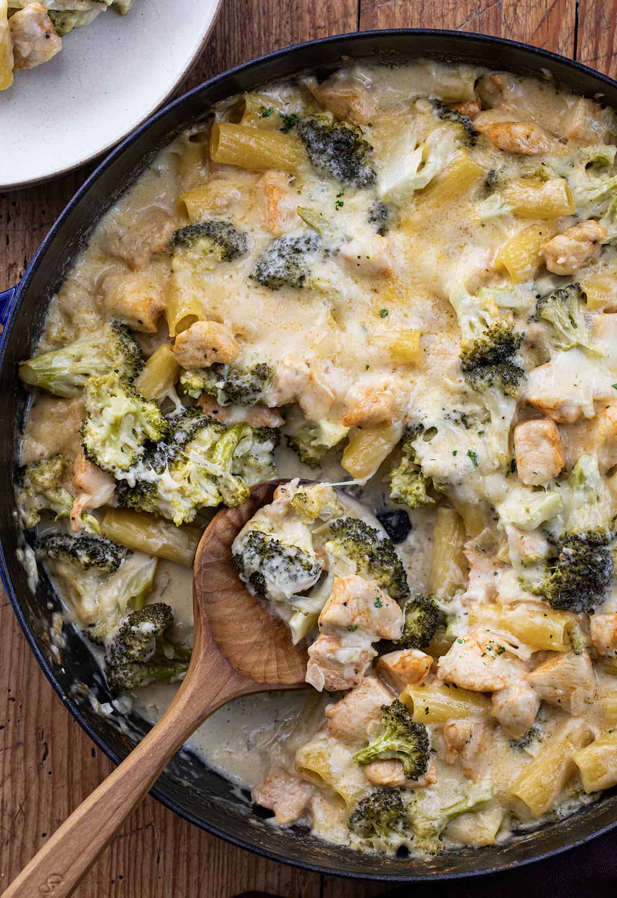 Pan of Chicken and Broccoli Pasta from Overhead with Wooden Spoon in it and Some Missing.