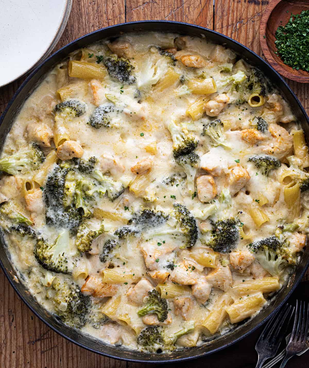 Chicken and Broccoli Pasta in a Skillet on a Wooden Cutting Board.