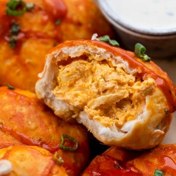 Buffalo Chicken Bombs in a Pan with Ranch Dressing and One Bomb Cut in Half Showing the Inside After Baking.
