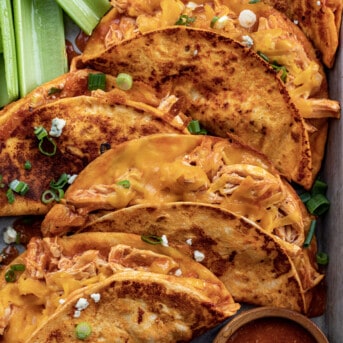 Buffalo Chicken Tacos on a tray from overhead with sauce and celery.