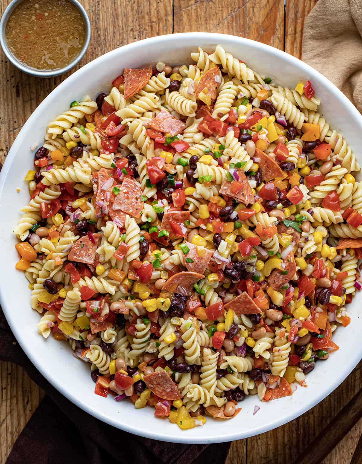 Bowl of Cowboy Caviar Pasta Salad in a White Bowl on a Wooden Cutting Board.