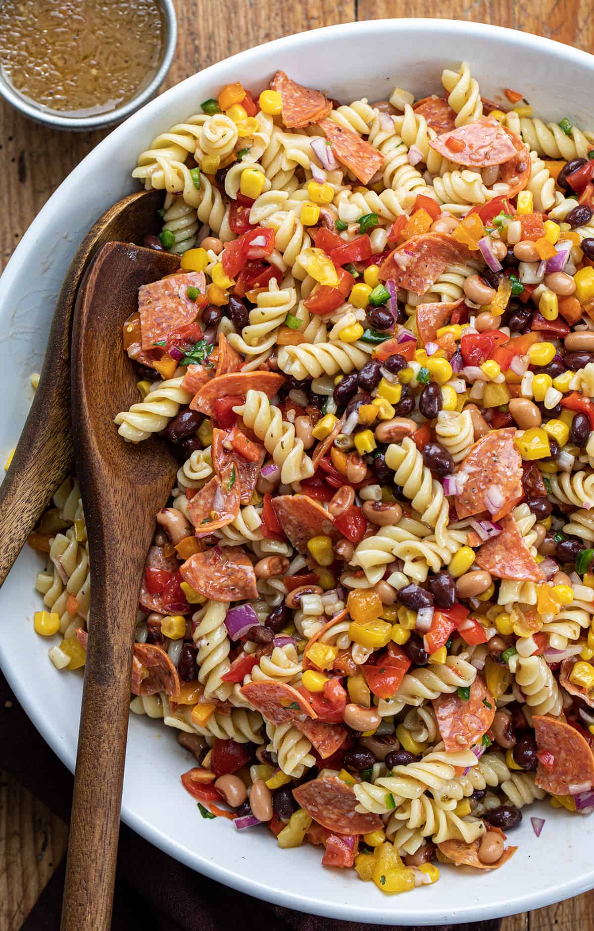 Bowl of Cowboy Caviar Pasta Salad with Wooden spoons Tucked in the Side.