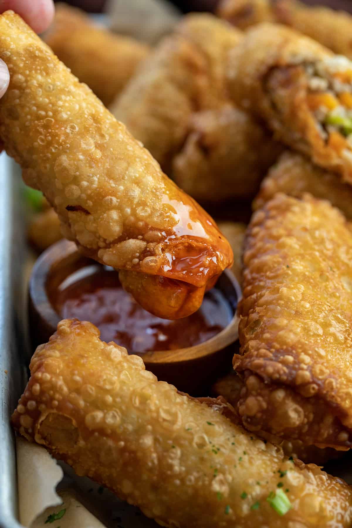 Dipping a Homemade Egg Roll into Sweet Chili Sauce.