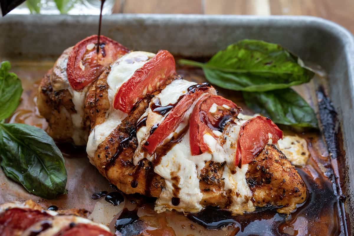 Pouring a Balsamic Glaze Reduction Over Caprese Hasselback Chicken.