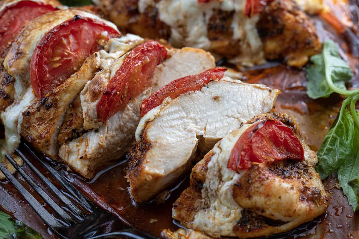 One piece of Caprese Hasselback Chicken Cut and Showing Juicy Inside.