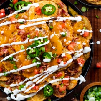 Skillet of Irish Nachos Covered in Toppings and Sour Cream.