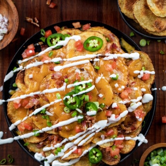 Skillet of Irish Nachos Covered in Toppings and Sour Cream.