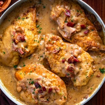 Smothered Chicken in a Pan with Bacon Bits on a Cutting Board.