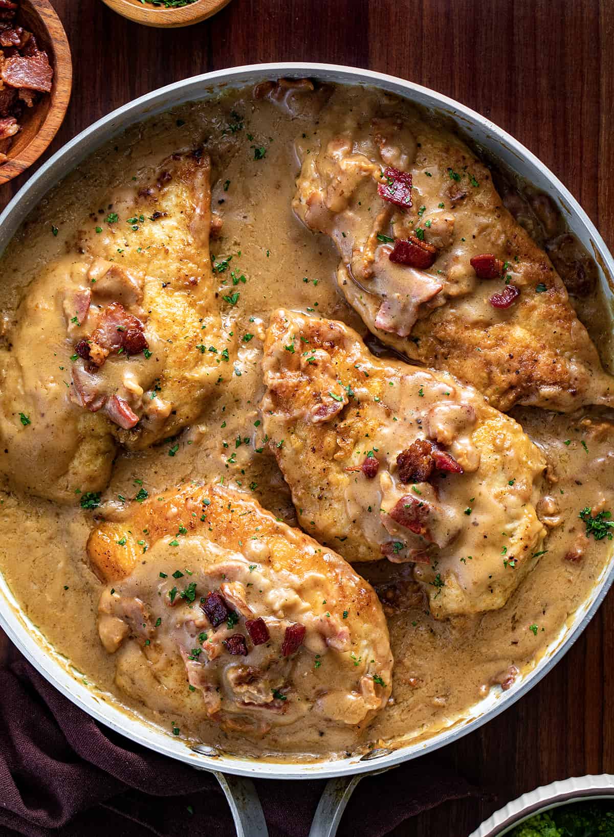Smothered Chicken in a Pan with Bacon Bits on a Cutting Board. 
