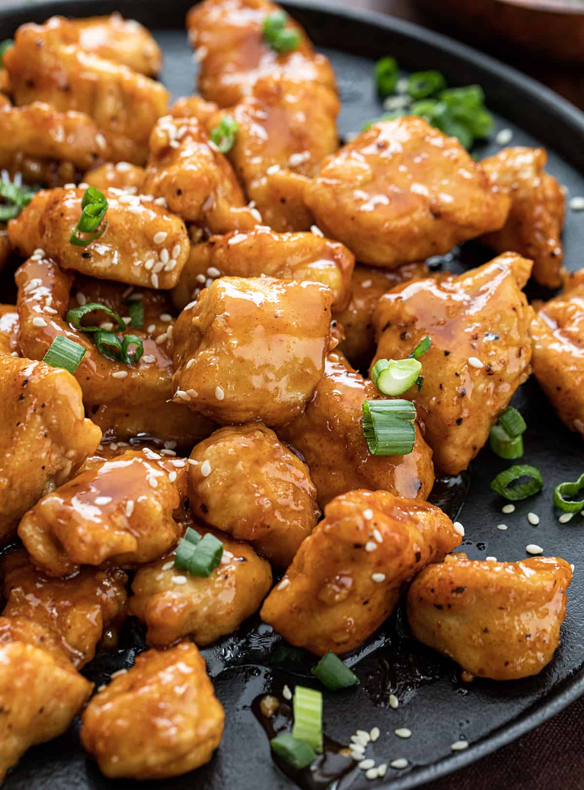 Close up of Sweet Chili Chicken on a Black Skillet with Green Onions.