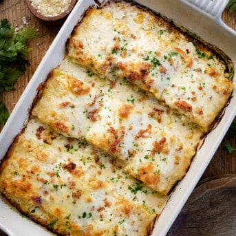 Overhead of Chicken and Broccoli Alfredo Roll-Ups in a Baking Dish on a Cutting Board.