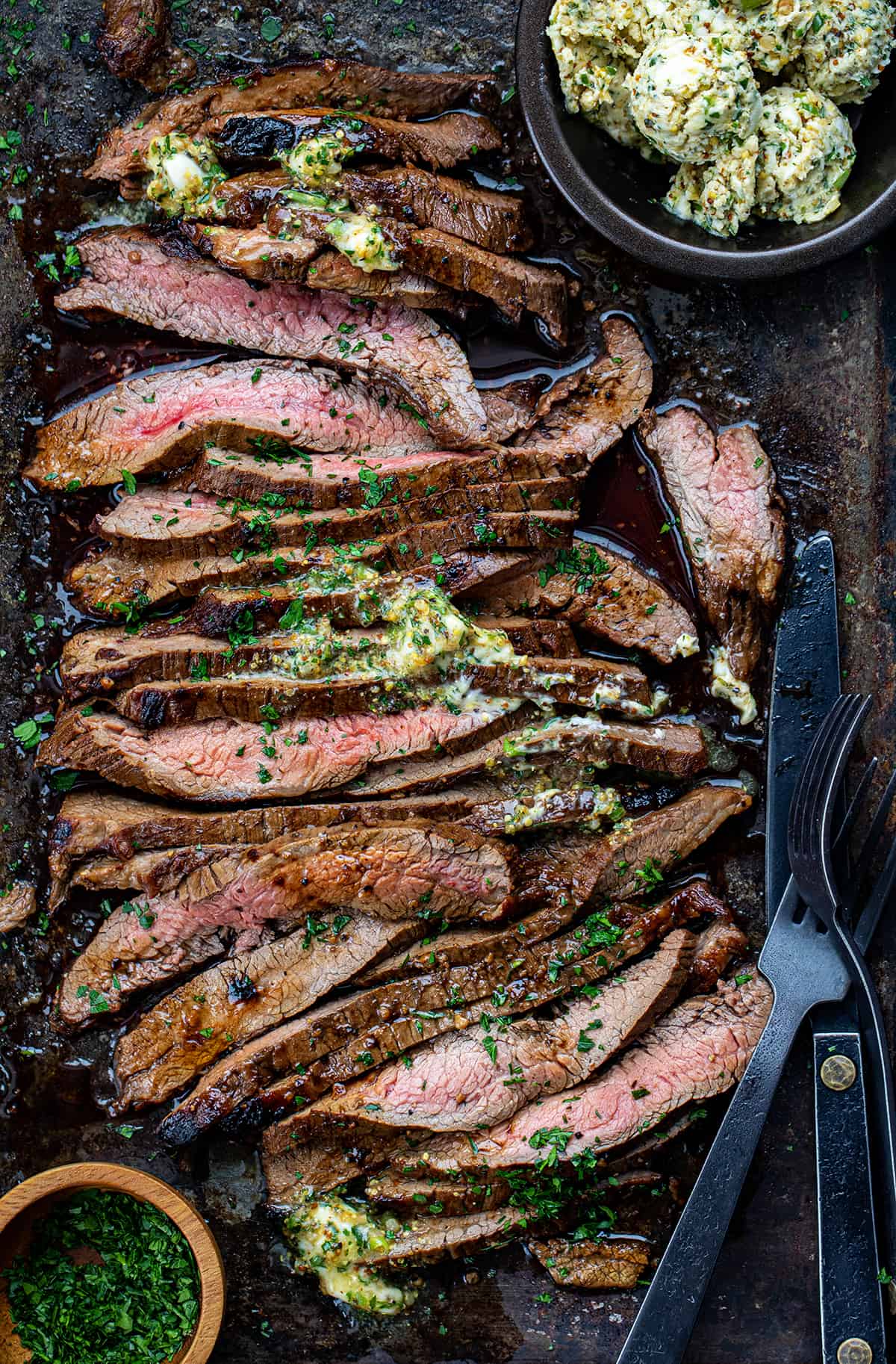 Cut up London Broil on a Sheet Pan with Melted Cowboy Butter and Silverware.