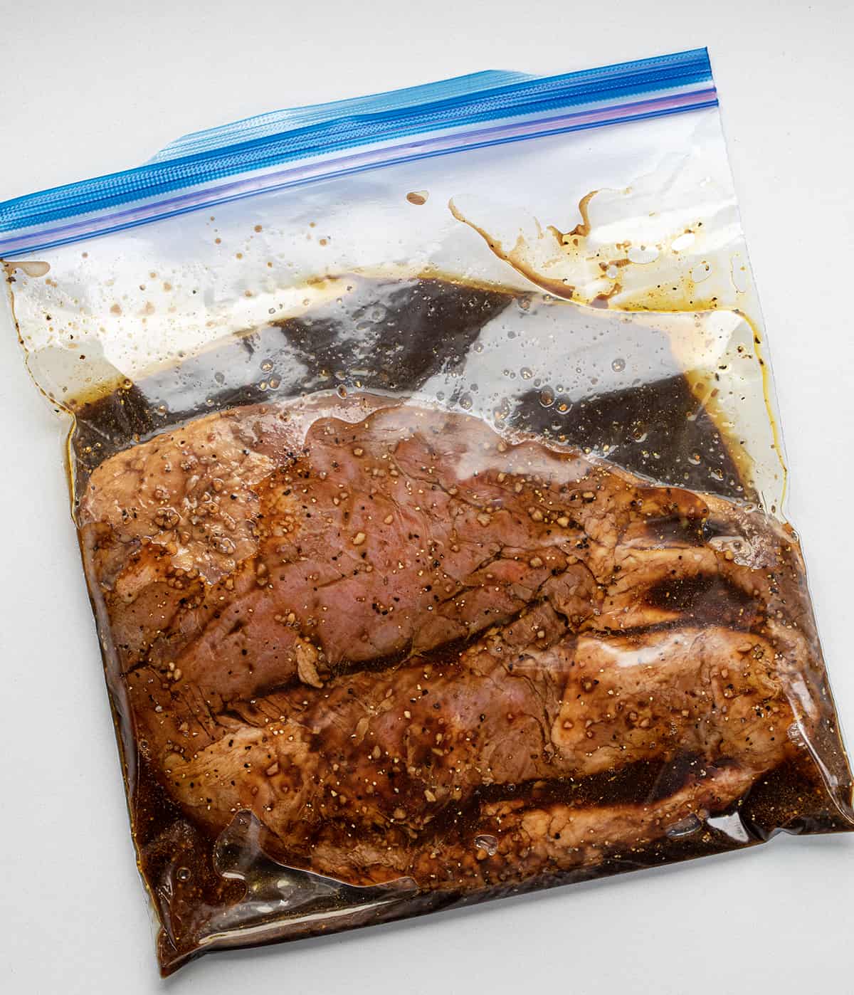 Bag of raw flank steak soaking in marinade for a London Broil. 