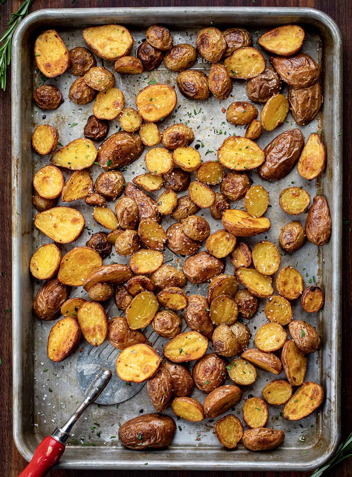 Sheet Pan Covered in Roasted Potatoes After They have Baked with a Spatula.