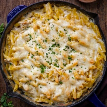 Skillet filled with Chicken Alfredo Bake on a Cutting Board with Garnish.