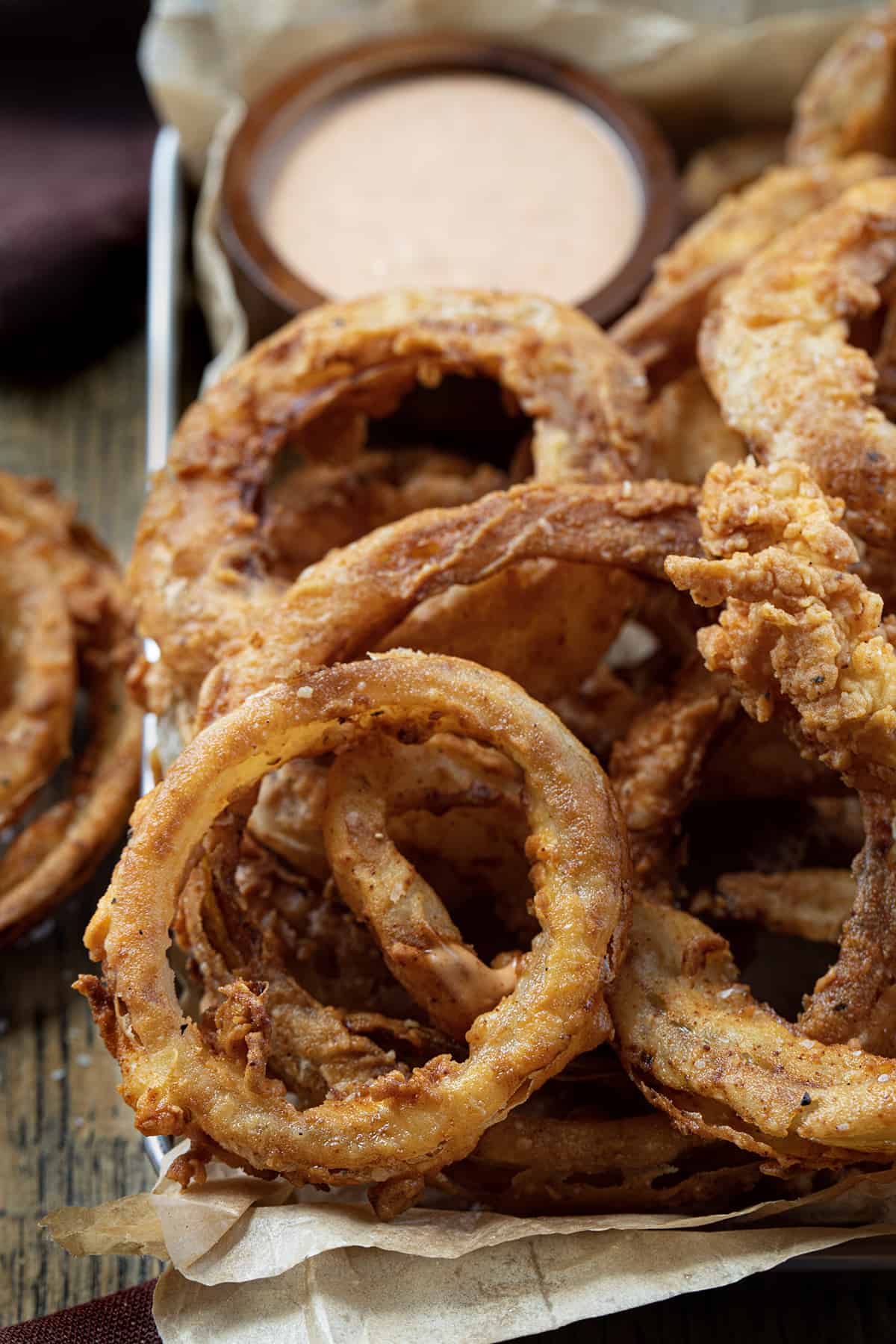 Close up of Onion Rings in a Platter with Fry Sauce in the Back.