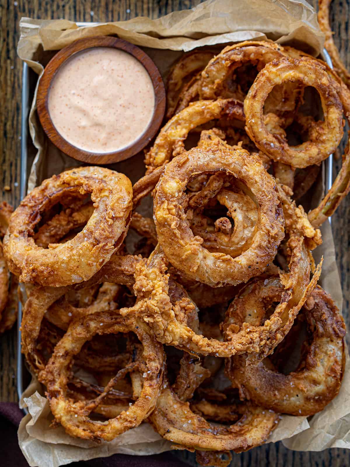 Pan of Onion Rings with Fry Sauce on Crumpled Parchment Paper from Overhead. 