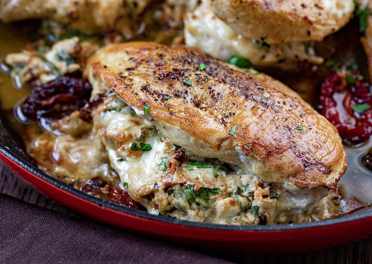 Close up of Stuffed Sun-Dried Tomato Chicken in Red Skillet.