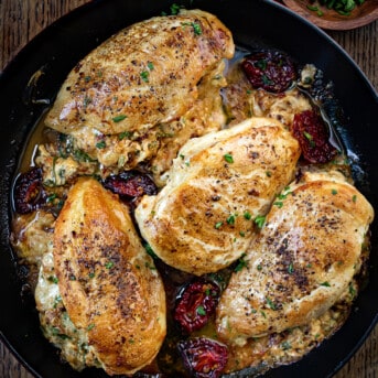 Skillet of Stuffed Sun-Dried Tomato Chicken on a Cutting Board.