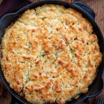 Butter Swim Biscuits and Gravy Bake in a Black Staub Skillet on a Wooden Cutting Board with Coffee.