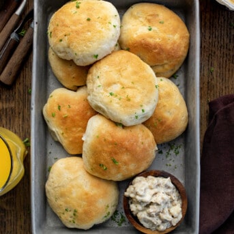 Pan Full of Seasoned Biscuits and Gravy Bombs on a Dark Cutting Board with OJ.