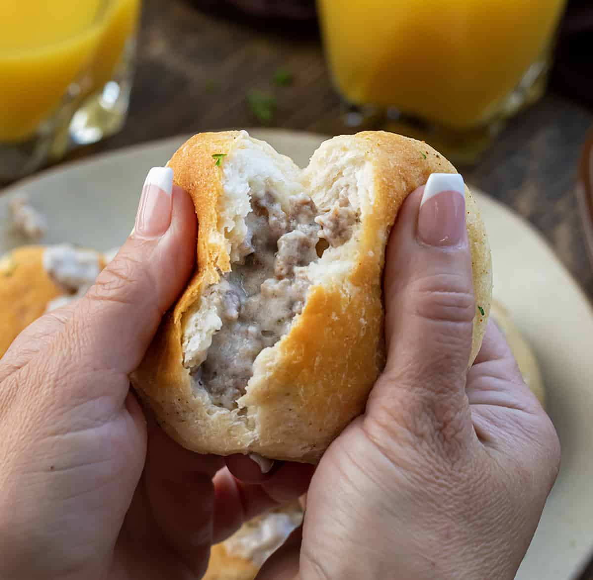 Hand Holding and Tearing a Seasoned Biscuits and Gravy Bomb.