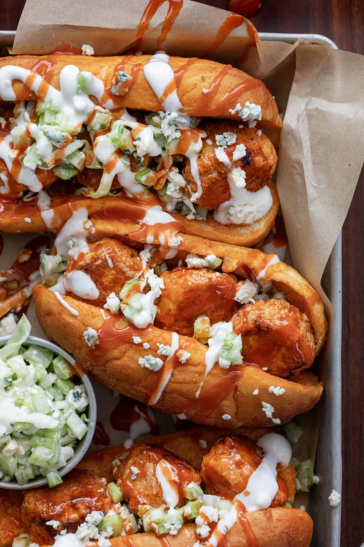 Buffalo Chicken Meatball Sandwiches in a Pan on a Dark Cutting Board.