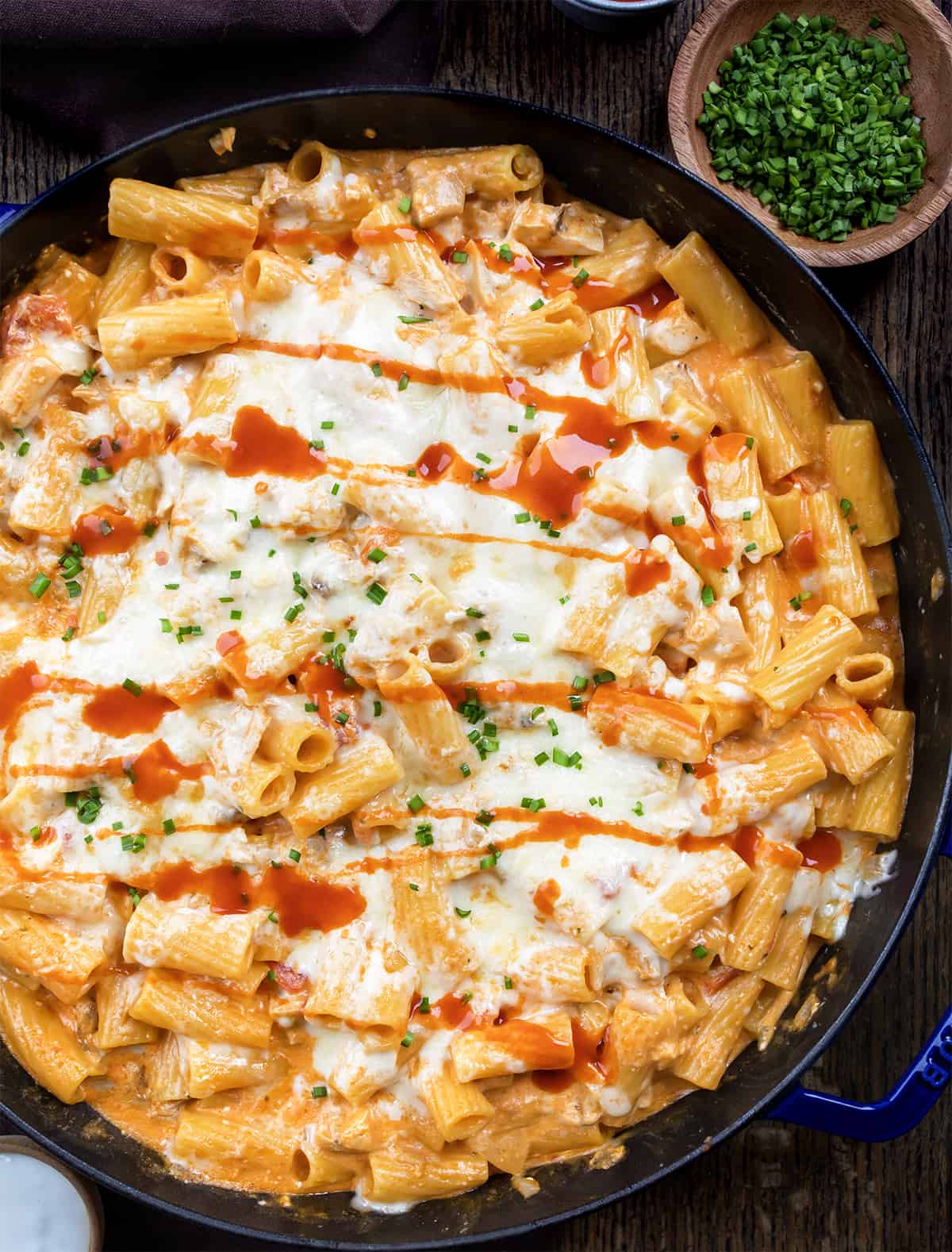 Skillet of Buffalo Chicken Pasta on a Dark Cutting Board.