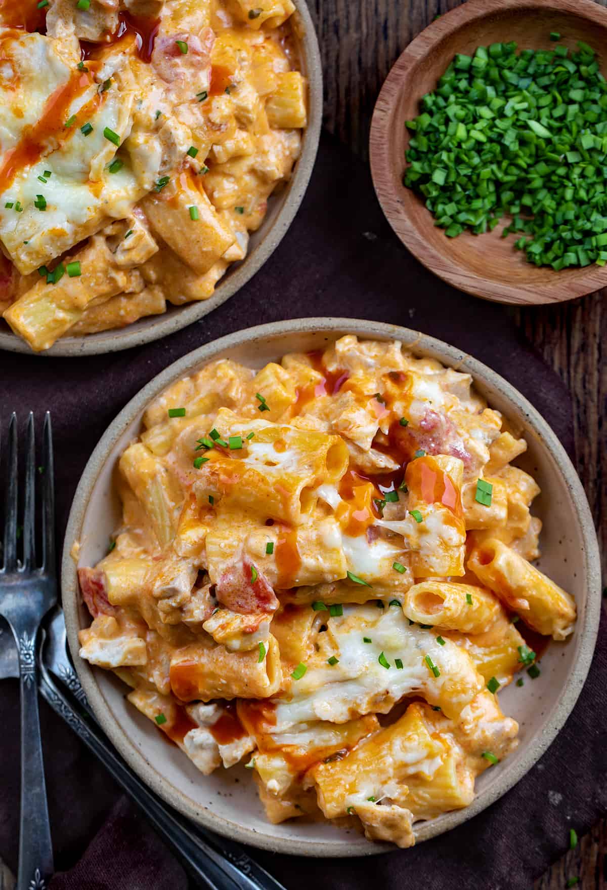 Plates of Buffalo Chicken Pasta on a Dark Cutting Board.