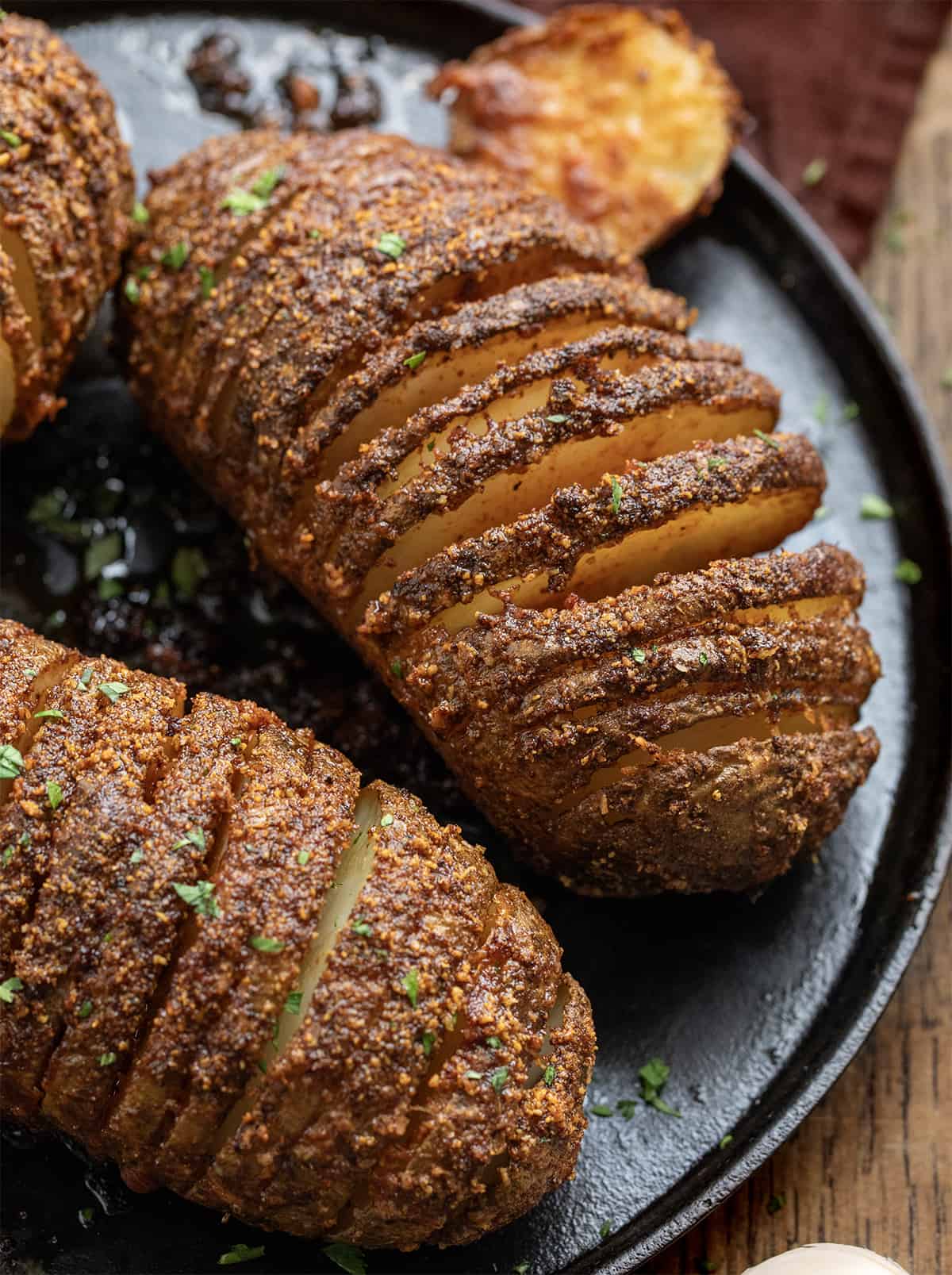 Crispy Garlic Parmesan Hasselback Potatoes on a Black Skillet and Showing Layers.