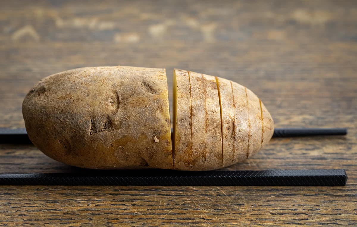 How to Cut a Hasselback Potato Using a Sharp Knife and Chopsticks.