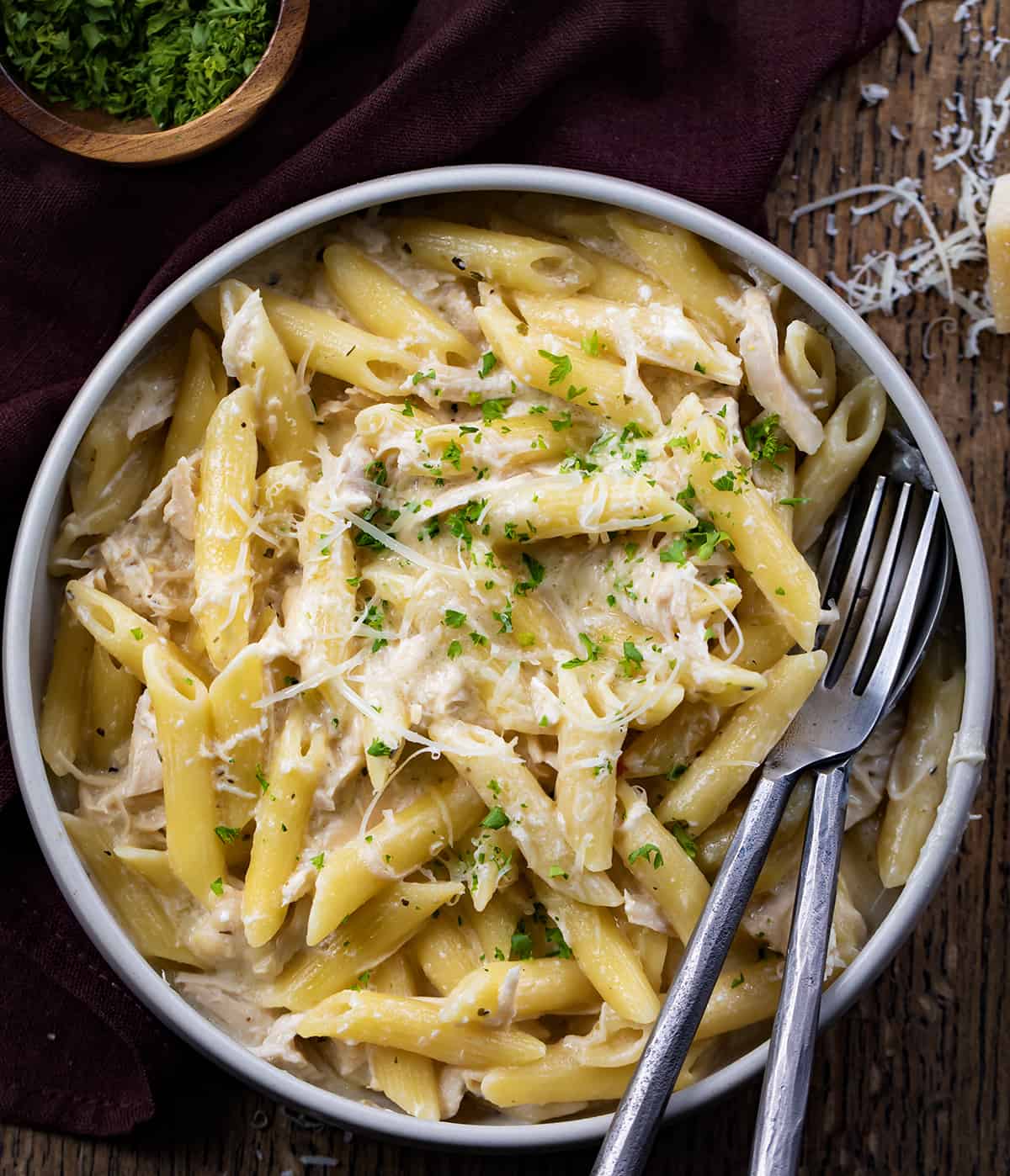 Bowls of Olive Garden Chicken Pasta on a Dark Cutting Board with Silverware.