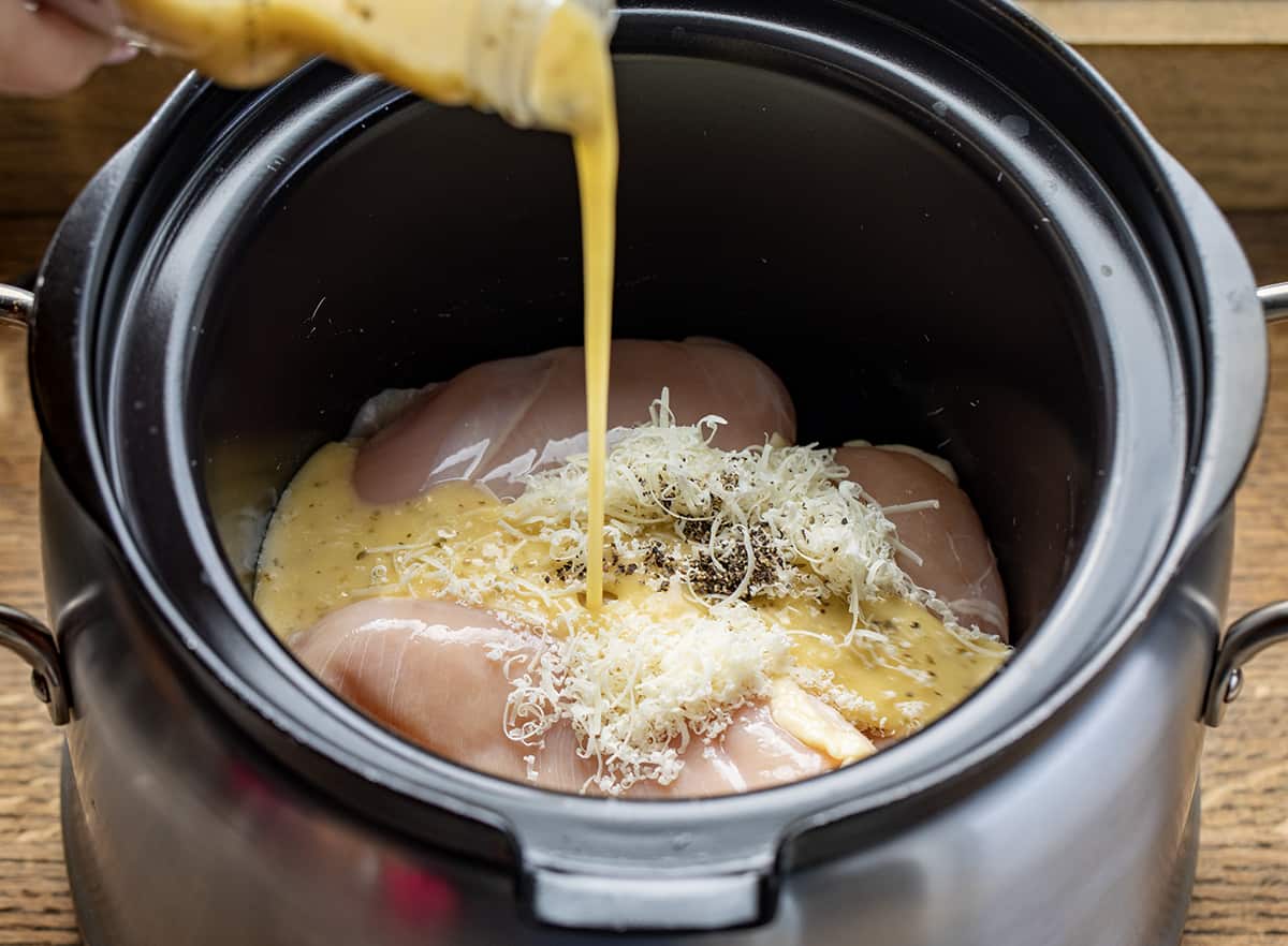 Pouring Olive Garden Dressing Over Chicken and Spices in a Slow Cooker.