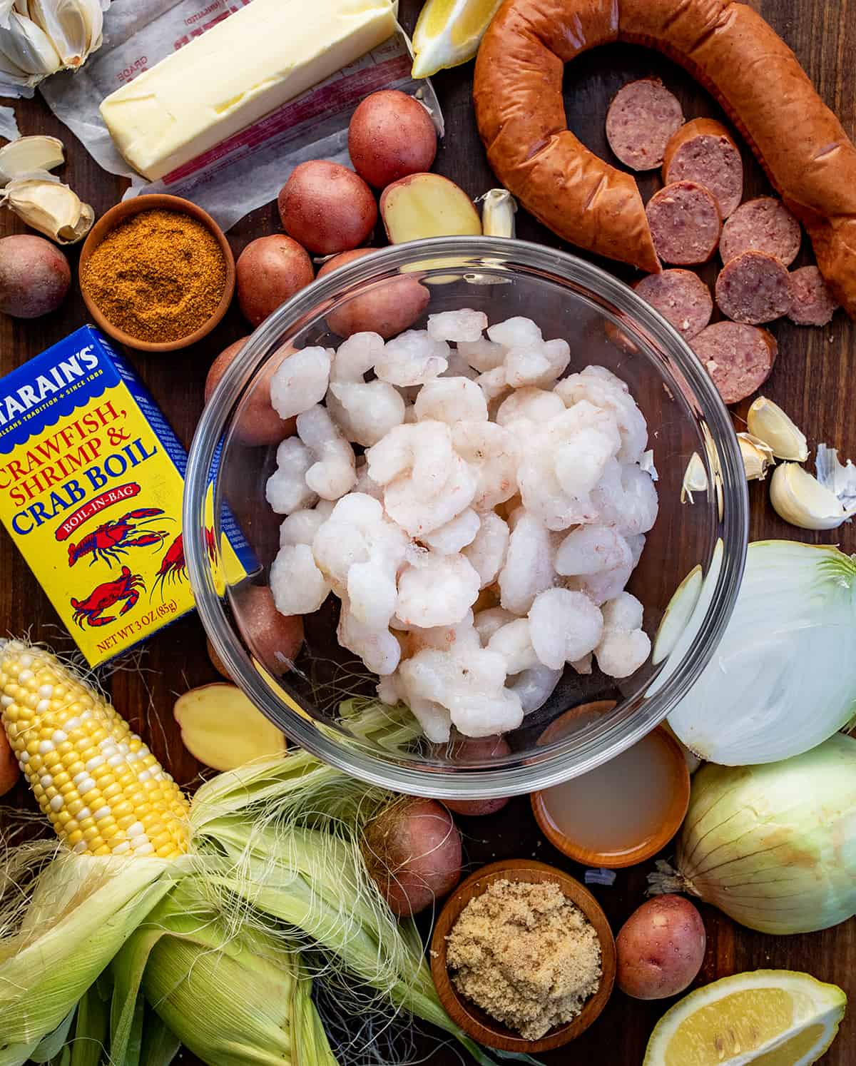 Raw Ingredients Needed to Make Easy Shrimp Boil on a Dark Cutting Board. 