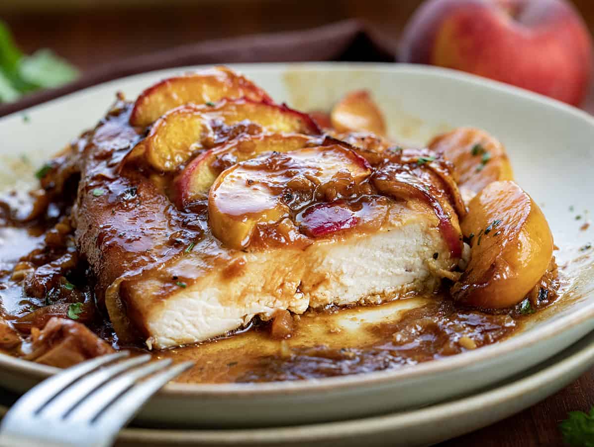 Piece of Roasted Peach Chicken on a Plate with a Bite Removed Showing the Texture of the Cooked Chicken.