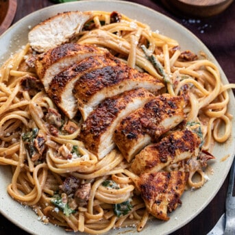 Plate of Spicy Tuscan Chicken Pasta with Sliced Chicken on a Bed of Creamy Noodles.