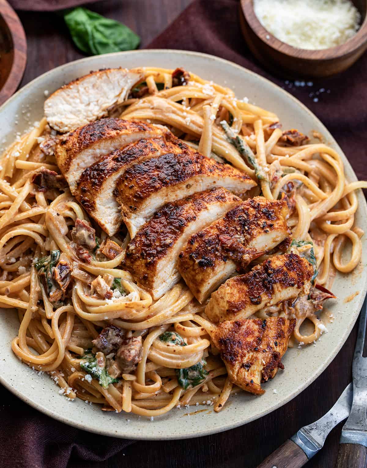 Plate of Spicy Tuscan Chicken Pasta with Sliced Chicken on a Bed of Creamy Noodles.