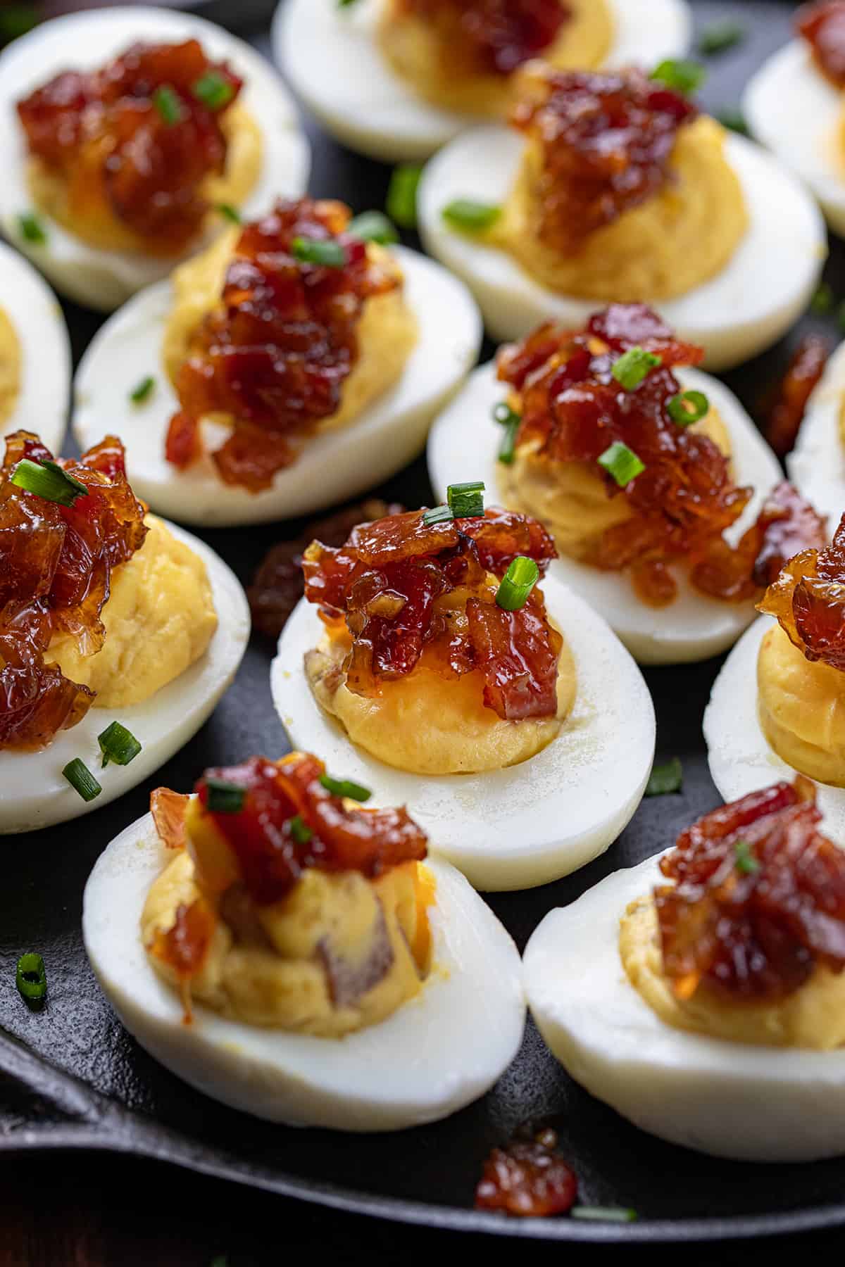 Close up of Whiskey Bacon Jam Deviled Eggs on a Dark Skillet.