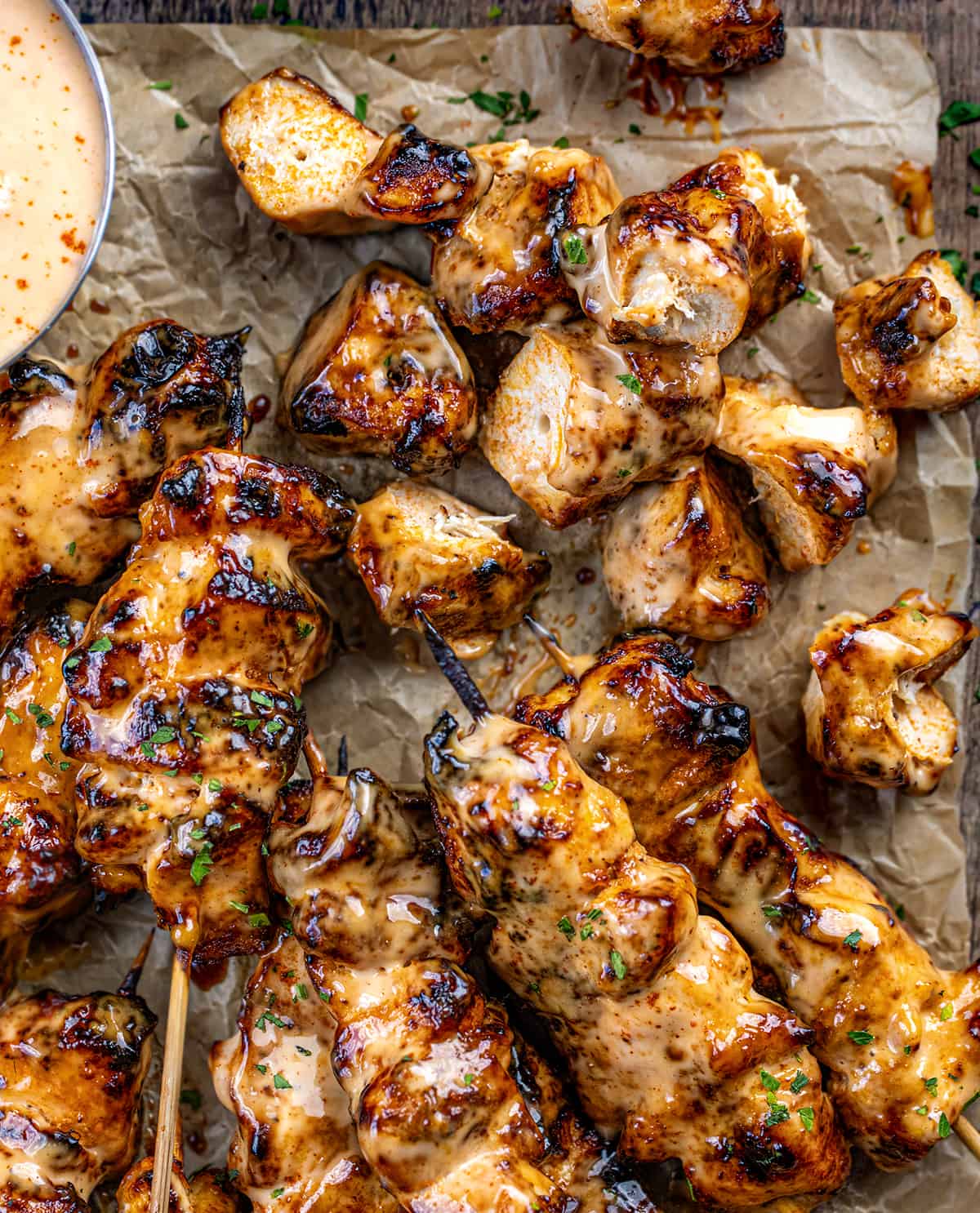 Bang Bang Chicken Skewers on Parchment with a Few Pieces of Chicken not on the Skewer.