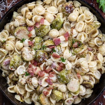 Skillet of Roasted Brussels Sprouts Bacon Pasta on a wooden table from overhead.