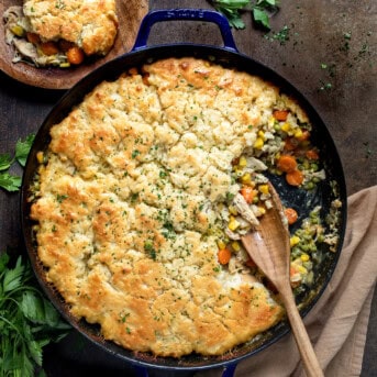 Skillet of Butter Swim Biscuit Chicken Pot Pie with Some Removed and a Wooden Spoon.