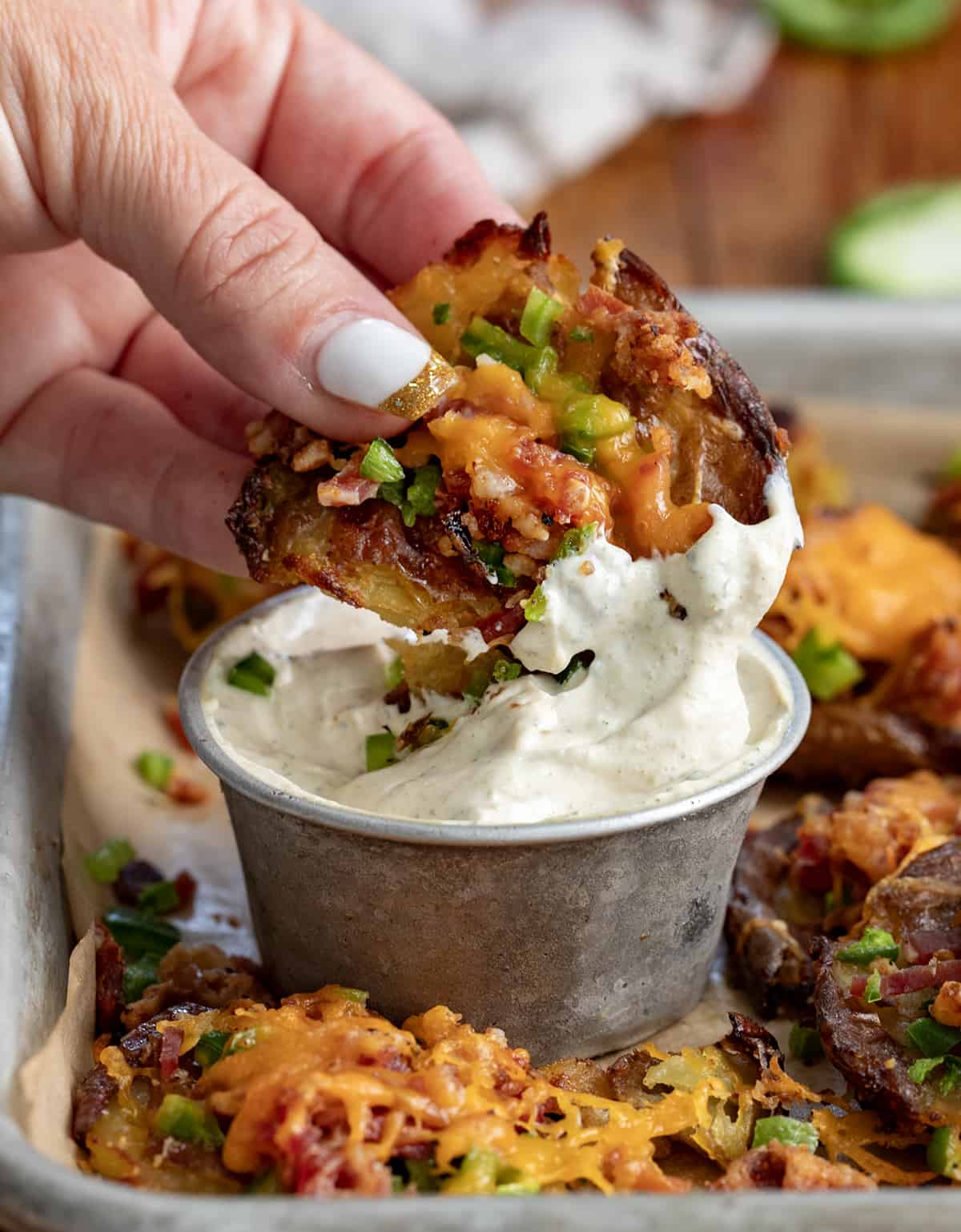 Hand Dipping a Jalapeno Popper Smashed Potato into Sauce.