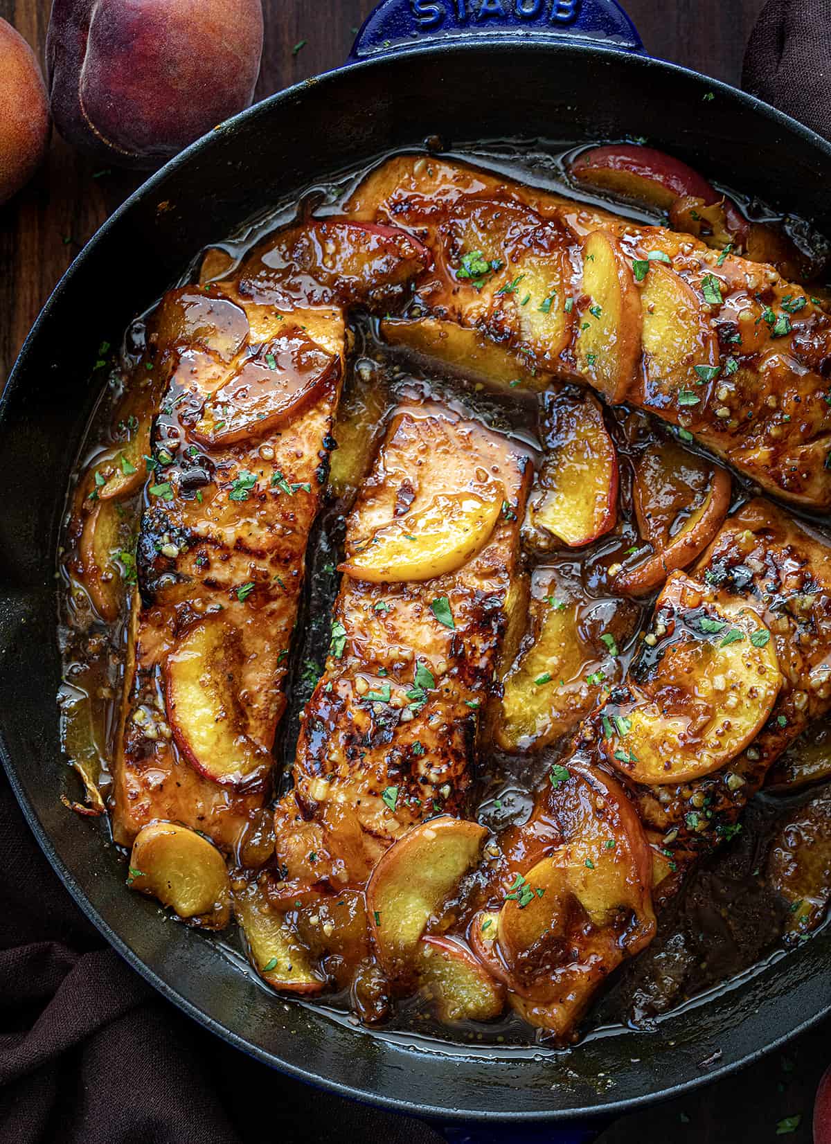 Bourbon Peach Roasted Salmon in a Skillet from Overhead on a Dark Cutting Board.