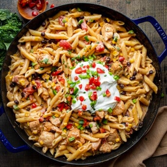 Skillet of Southwest Chicken Pasta with a Dollop of Sour Cream and Tomato and Jalapeno Garnish.