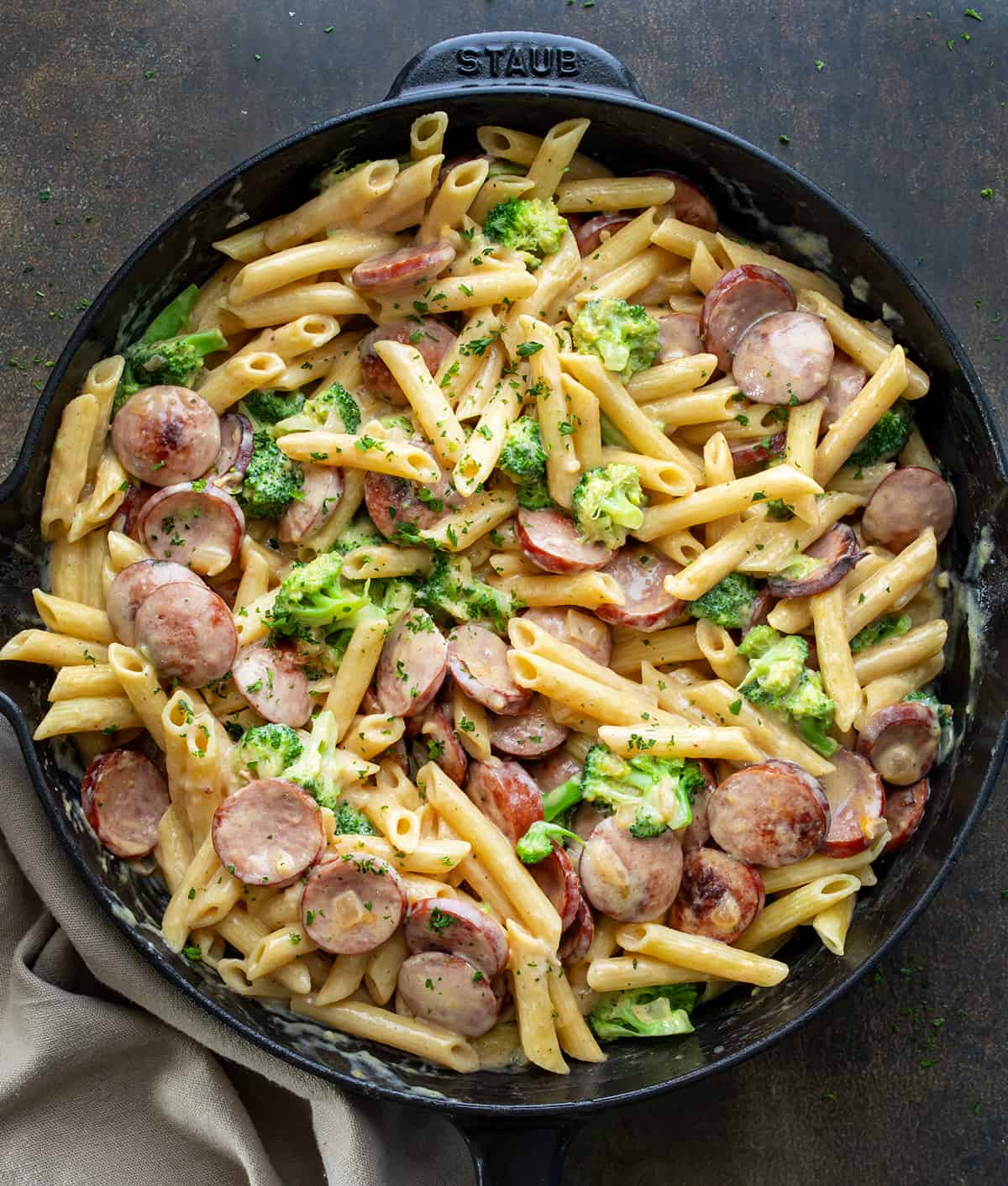 A Creamy Kielbasa Broccoli Skillet on a Dark Table from Overhead. 