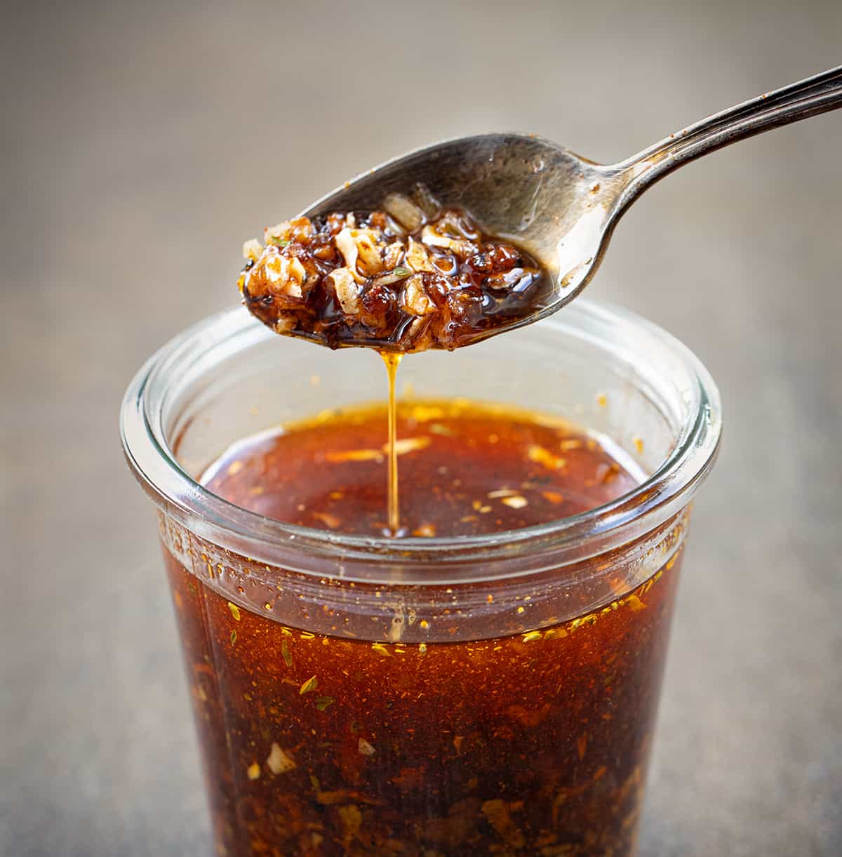 Spoon with Creole Garlic Chili Oil on It Above a Jar.