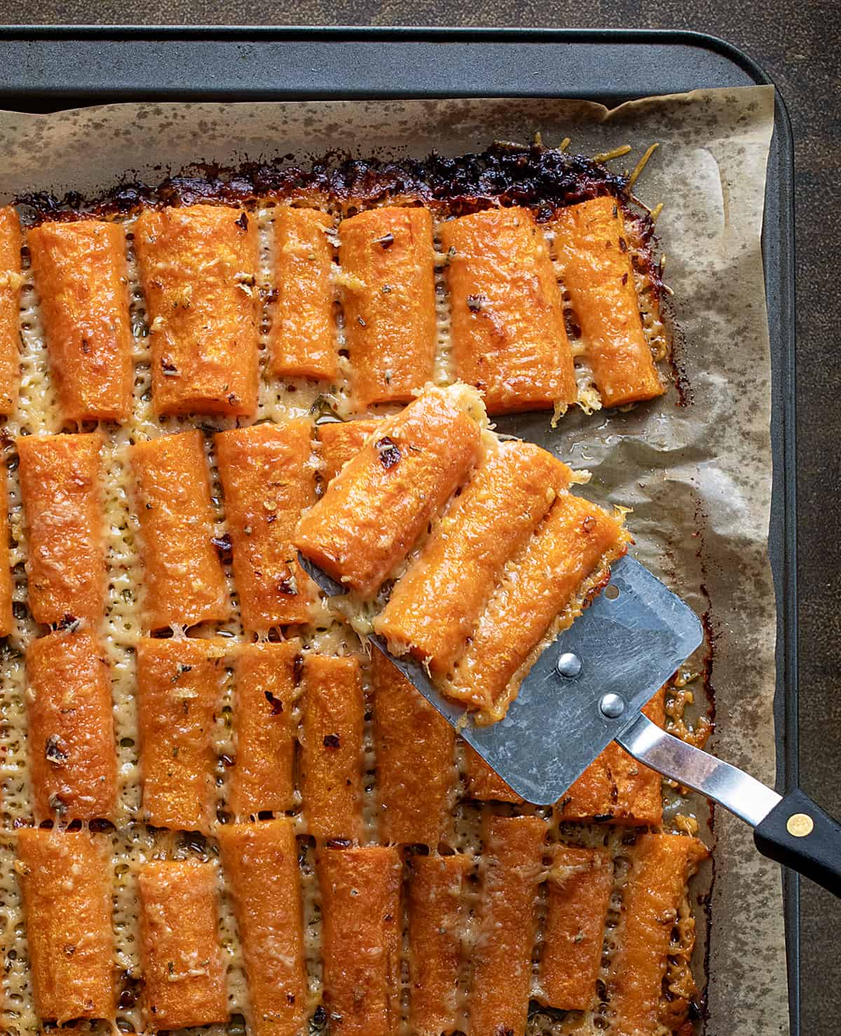 Spatula Picking up Crispy Parmesan Carrots from Sheet Pan.