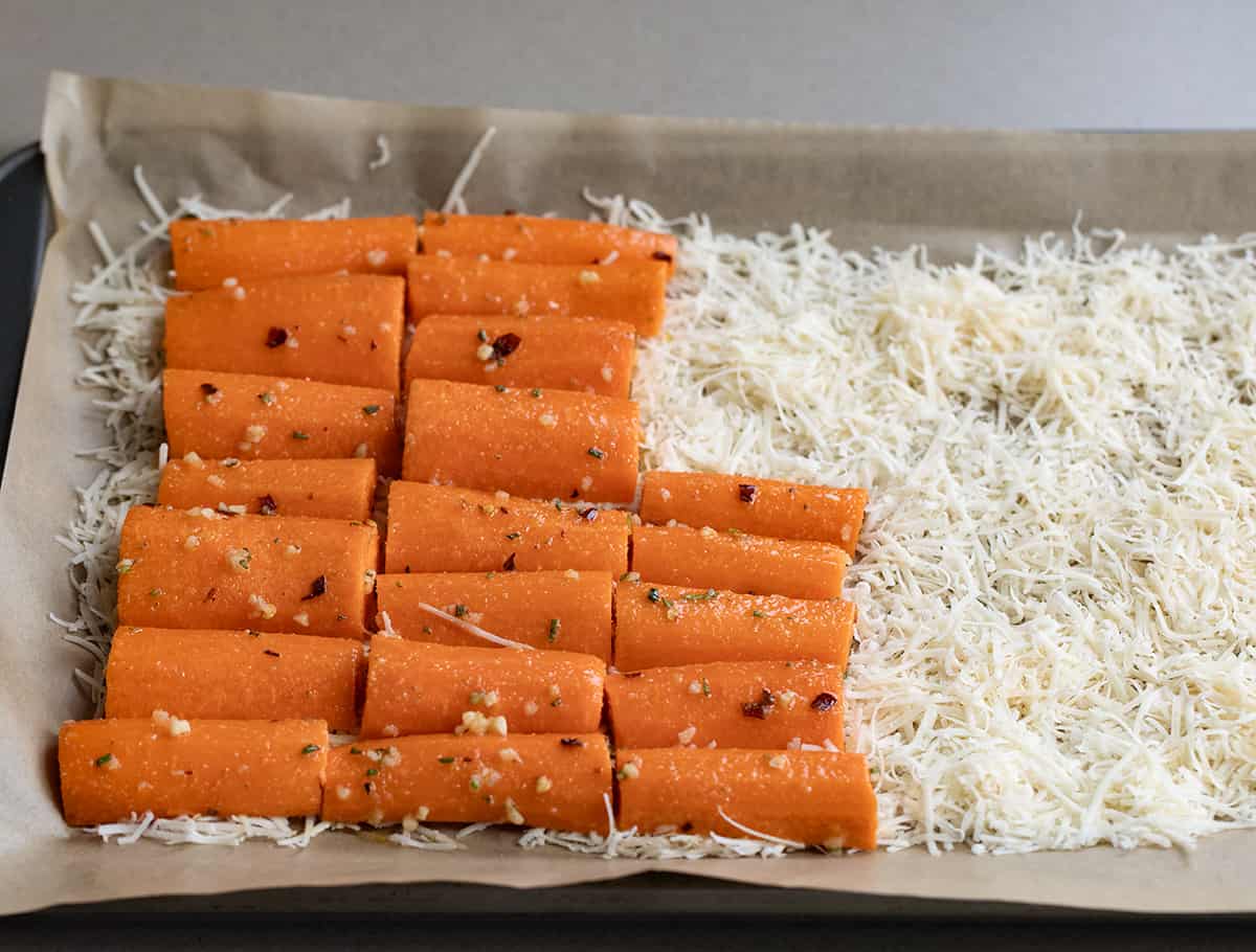 Laying Raw Seasoned Carrots on Parmesan to Make Crispy Parmesan Carrots.
